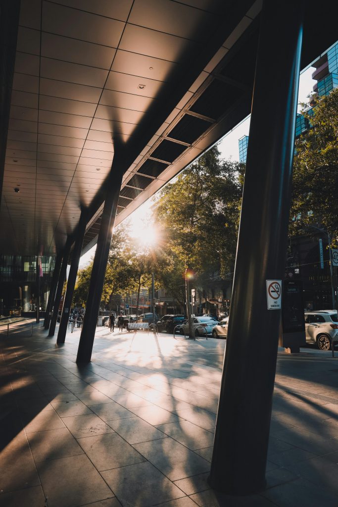A vibrant urban scene in Melbourne, Australia, with dramatic shadows and sunset light.